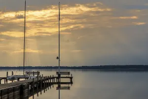 Northern Germany Scenery Prints: A bench on a jetty with the evening sun shining through the clouds