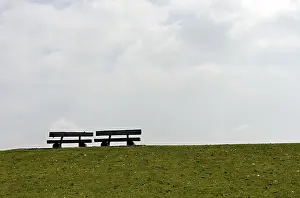 Seating Accommodation Europe Prints: Two empty benches on a dike crest against the light