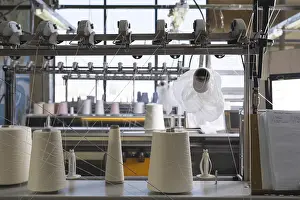 Industrial Building Architecture Prints: Big spools with white thread at rewinding machine view