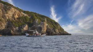 Morning Light Coastline Prints: A boat moves along the coast with distinctive cliffs under a sky full of dramatic clouds