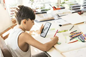 Online Education Prints: A boy is learning to draw with her smart phone