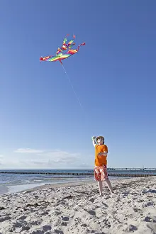 Seaside Resort In Germany Prints: Boy playing with a kite on the beach