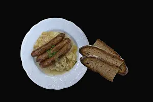 Dark Background Food Images Prints: Bratwurst with cabbage and bread on a black background