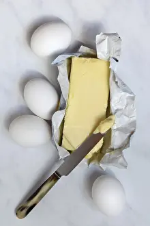 Plain Colored Background Food Still Life Prints: Butter in opened packaging and eggs