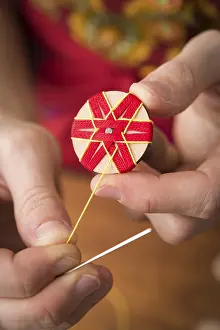 Traditional Bavarian Crafts Prints: Button maker stitching and wrapping red and yellow yarn into star pattern