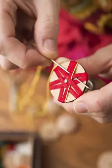 Regional Handicrafts Prints: Button maker stitching and wrapping red and yellow yarn into star pattern