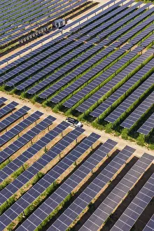 European Renewable Energy Prints: A car on a path between vast fields of solar panels