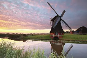 European Historic Landmark Prints: Charming windmill by river at dramatic sunrise