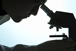 Indoor Studio Photography Prints: Chemist looking through a microscope