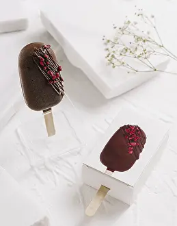 Elegant Desserts Prints: Two chocolate popsicles are displayed on a clean white surface