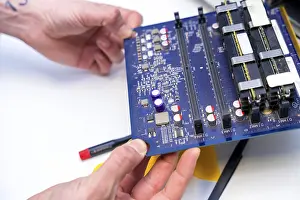 Quality Assurance Process Prints: Close-up of the hands of a technician holding an electronic component of computer in a workshop