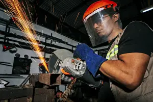 Handicraft Industry Tools Prints: Close-up of a man using a grinder on an anvil