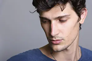 Man Looking At Camera Prints: Close up of young handsome man thinking while looking down