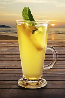 Alcoholic Mixed Drinks Prints: Cold citrus tea on the table with sunset view on background