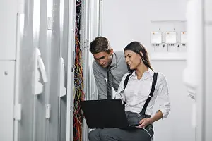Colleagues Working Together Prints: Colleagues working on maintaining a server room
