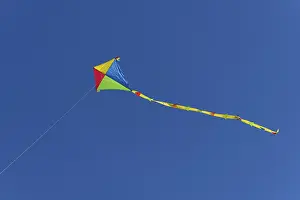 Deserted Seaside Resort Prints: Colourful kite in flight against a cloudless sky