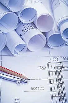 Architecture Design Prints: Compass pencil and big stack of white rolled up blueprints