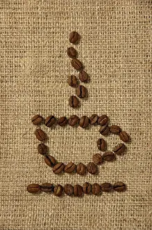 Coffee Concept Prints: Conceptual artistic pattern of a cup of coffee made from coffee beans on a sacking background