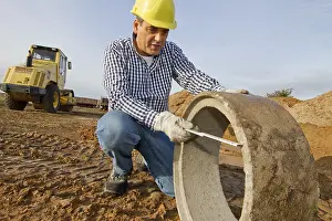 Yellow Hard Hat Prints: A construction worker checks a sewage pipe