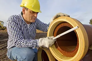 Protective Clothing For Workers Prints: A construction worker checks a sewage pipe