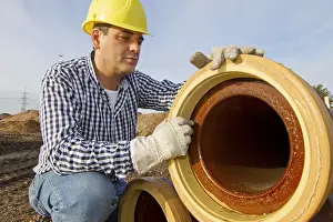 Yellow Hard Hat Prints: A construction worker checks a sewage pipe