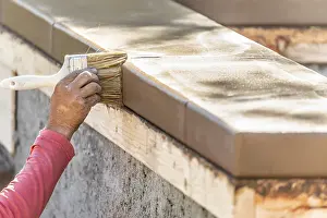 Construction Labor Prints: Construction worker using brush on wet cement forming coping around new pool