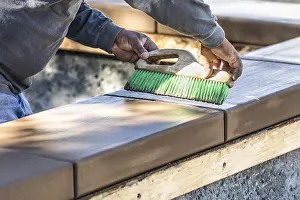 Cement Finishing Techniques Prints: Construction worker using brush on wet cement forming coping around new pool