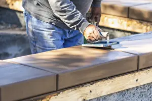 Construction Manpower Prints: Construction worker using hand groover on wet cement forming coping around new pool