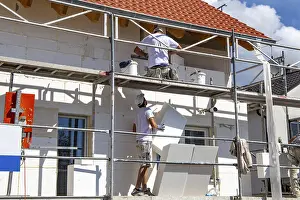 Residential Building Insulation Prints: Construction workers insulate a house facade