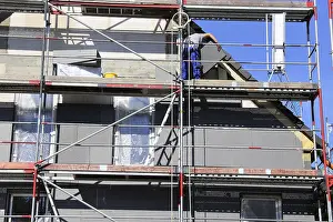 Construction Site Management Prints: Construction workers insulate a house facade