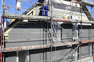 Energy Saving Construction Prints: Construction workers insulate a house facade
