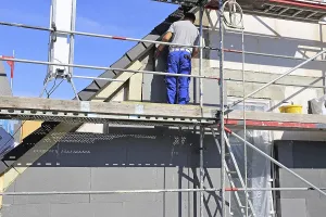 Exterior Wall Insulation Prints: Construction workers insulate a house facade