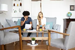 Modern Living Room Interior Design Prints: A couple sits on a sofa analyzing financial documents and using a calculator