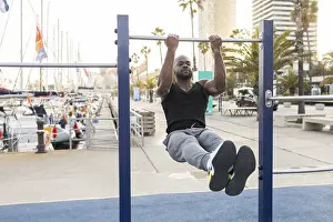 Pull Up Bar Workout Prints: A cuban man performs exercises on a pull up bar by a marina