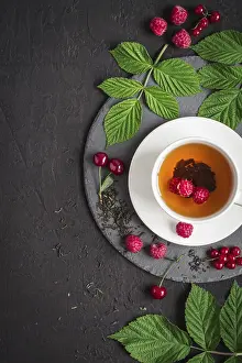 Black Background Food Prints: Cup of tea and ripe raspberry, cherry