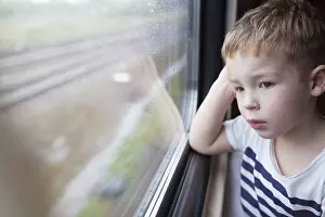 Boy Looking Out Window Prints: Curious boy looking out the window of a speeding train