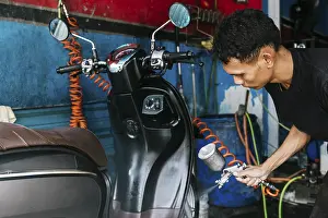 Cleanliness Importance Prints: A dedicated worker cleans a motorcycle using a sprayer in a vibrant workshop setting