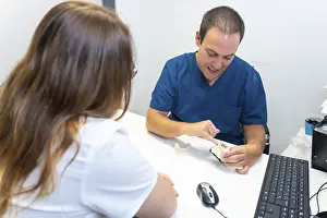 Healthcare Professional Advice Prints: Dental clinic, dentist explaining to a client the teeth to be implanted in a model