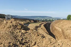 German Federal Republic Construction Site Prints: Digging for a pipeline with landscape in the background