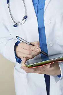 Female Doctor Portrait Prints: Doctor in white coat makes notes at work