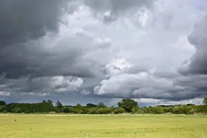 Cloud Formations Germany Prints: Dramatic cloud formations over a vast green meadow