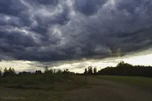 Weather Forecast Images Prints: Dramatic, dark clouds drift across a landscape at dusk