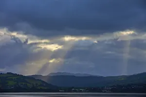 British Nature Photography Prints: Dramatic rays of light through a cloudy landscape over a lake