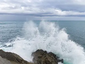 Rugged Coastline Scenery Prints: A dramatic scene as powerful waves collide with rugged rocks under a brooding sky
