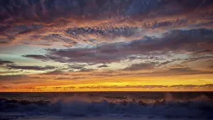 Atmospheric Light Of The Setting Sun Prints: Dramatic sunset with powerful cloud formations and breaking waves in the foreground