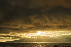 Warm Light Of The Setting Sun Prints: Dramatic sunset with sun rays breaking through the clouds over the sea