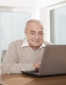 Man Smiling At Camera Prints: Elderly man using a PC