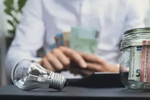 Pocket Calculator Use Prints: Electric light bulb. Man hands counting expenses bills on electricity banknotes of euro cash accounting on calculator