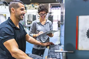Business Team Discussion Prints: Engineer and manager talking while using computer in a cnc metallurgic factory