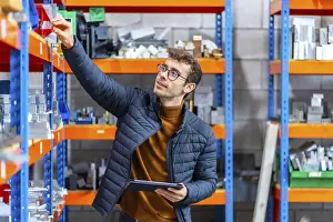 Industrial Building Architecture Prints: Engineer using tablet in the stock room of a computer numeric control modern factory